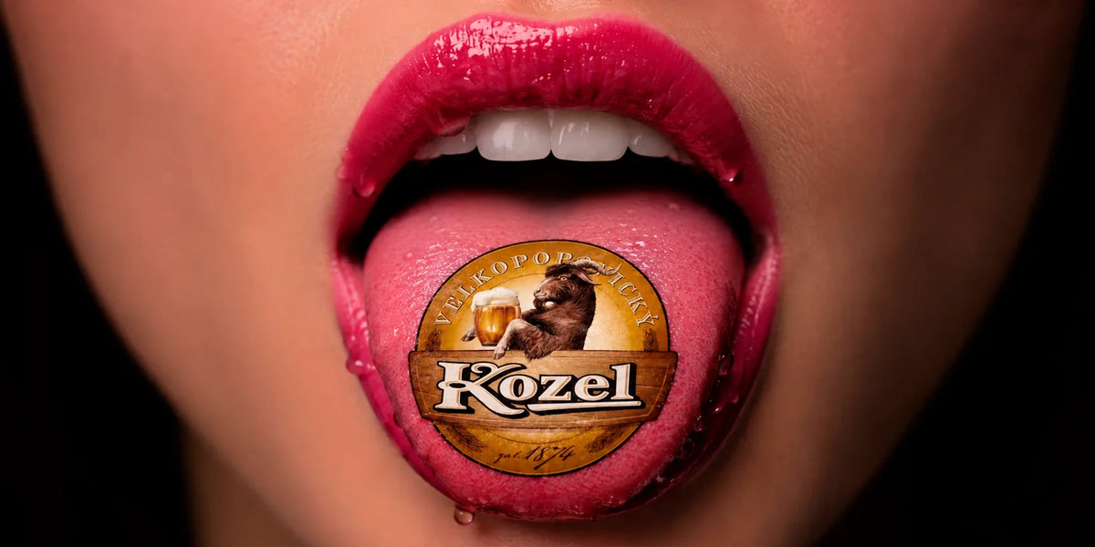 Creative Kozel beer advertisement featuring a close-up of glossy pink lips and tongue with the Velkopopovický Kozel logo centered against a dark background.